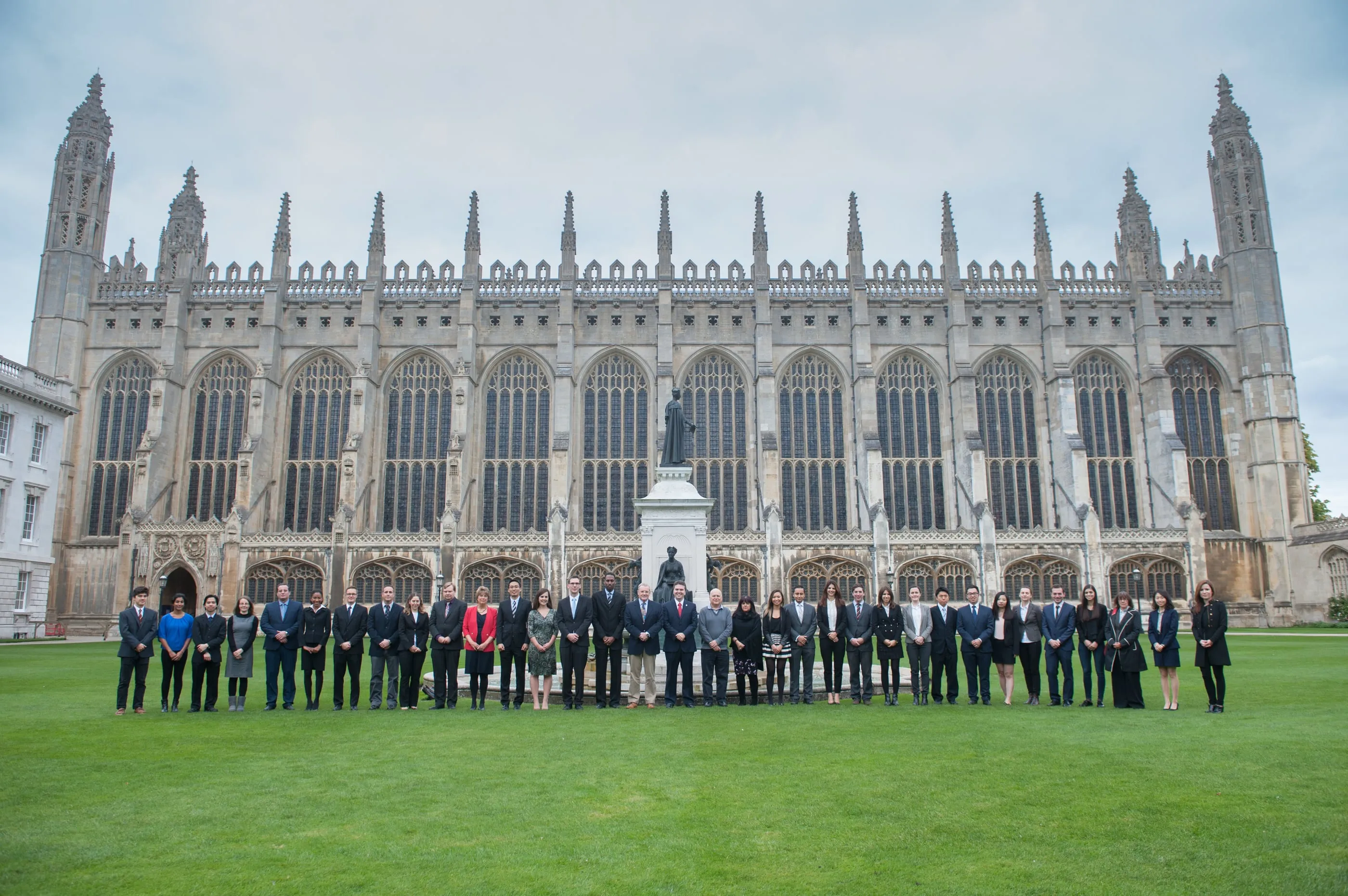 A large group photographed on a Cambridge college lawn in front of the chapel