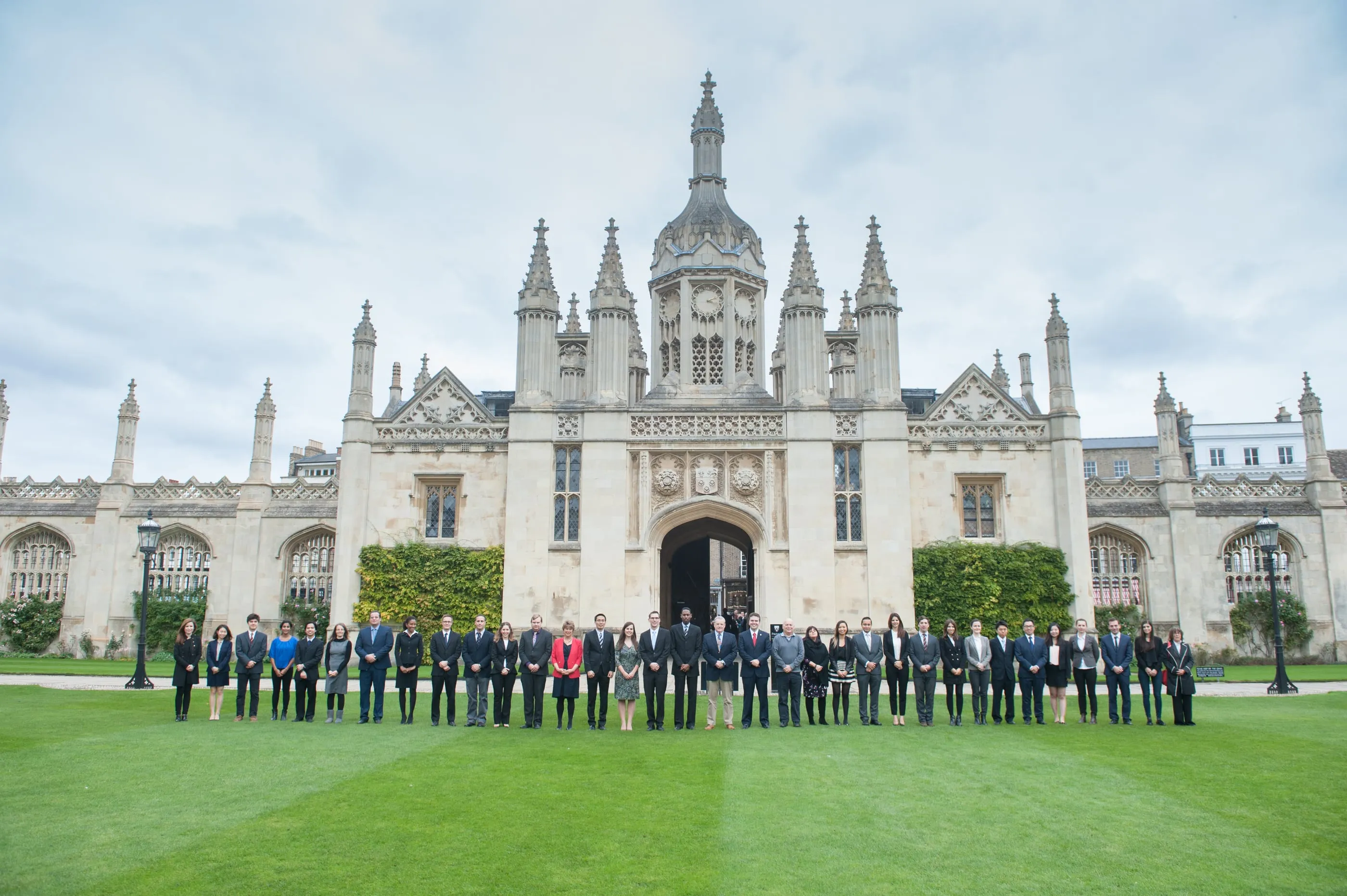A matriculation-style group photograph on a Cambridge college lawn