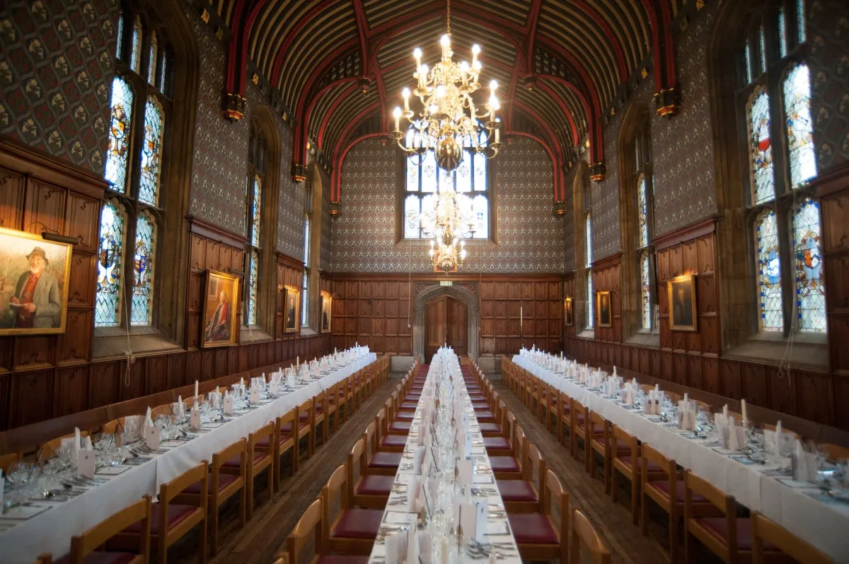 A Cambridge college hall laid for a formal dinner under the chandeliers