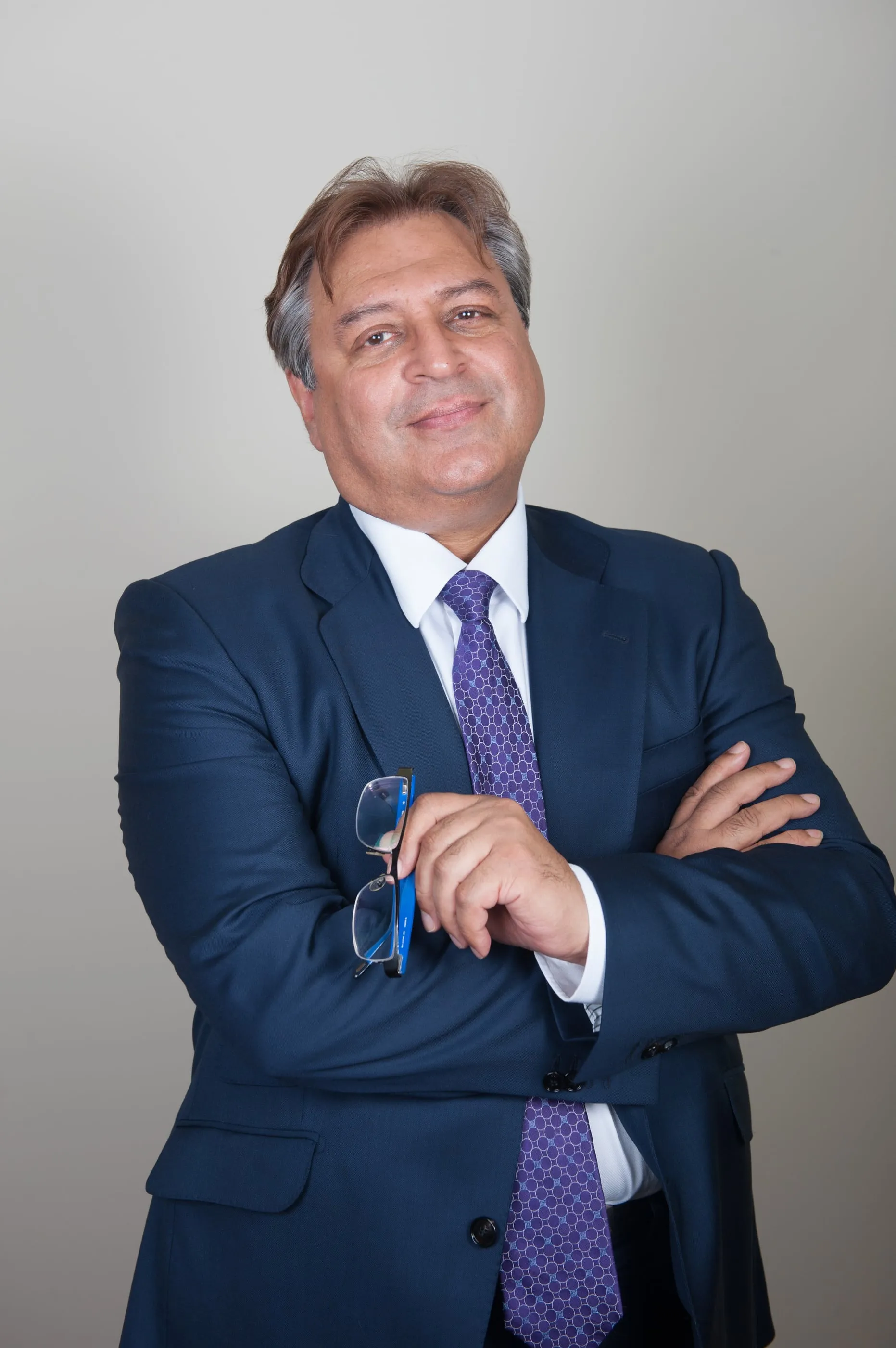 Executive portrait of a man in a dark suit with his arms folded