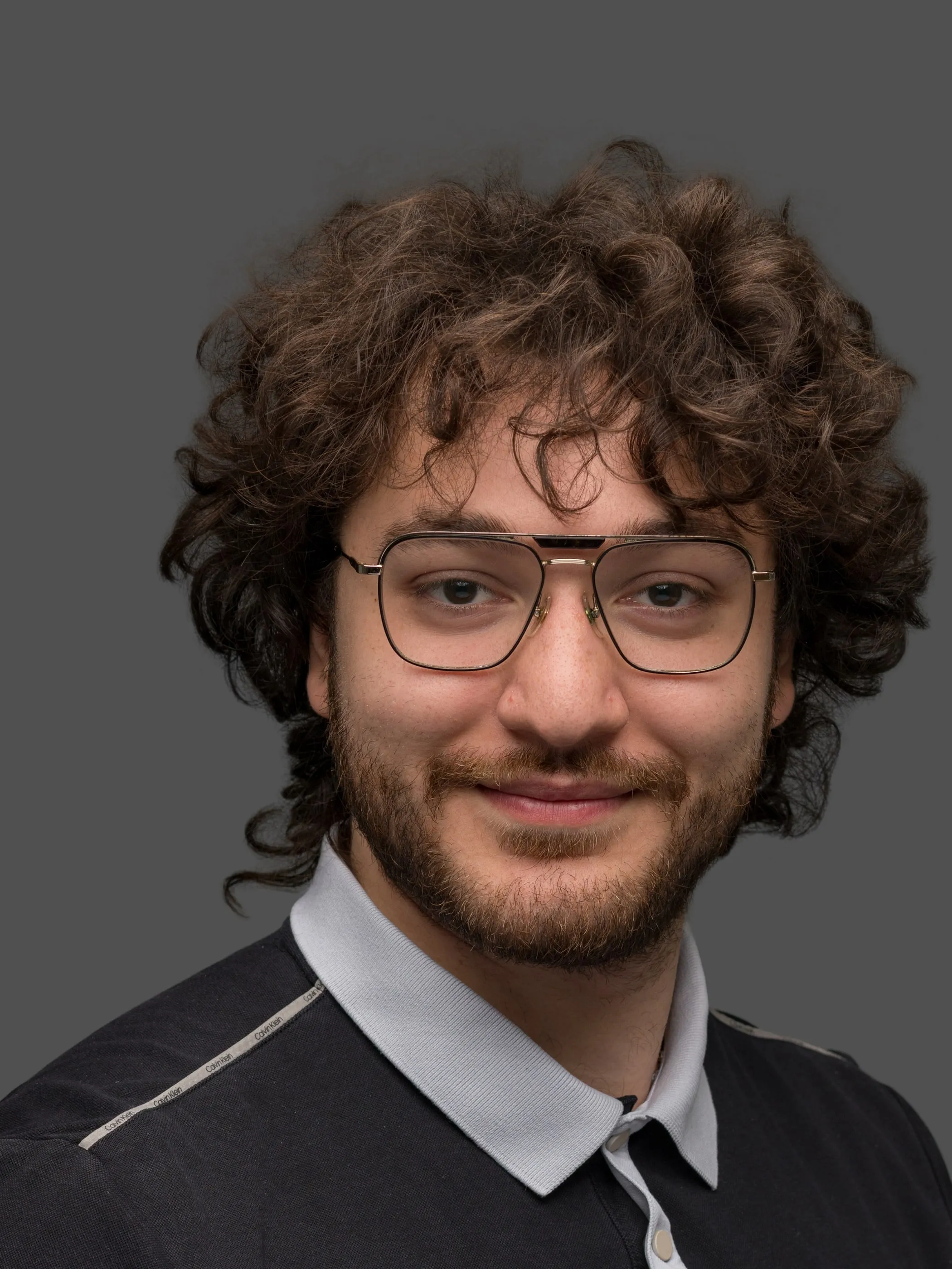 Corporate headshot of a man in glasses on a grey background
