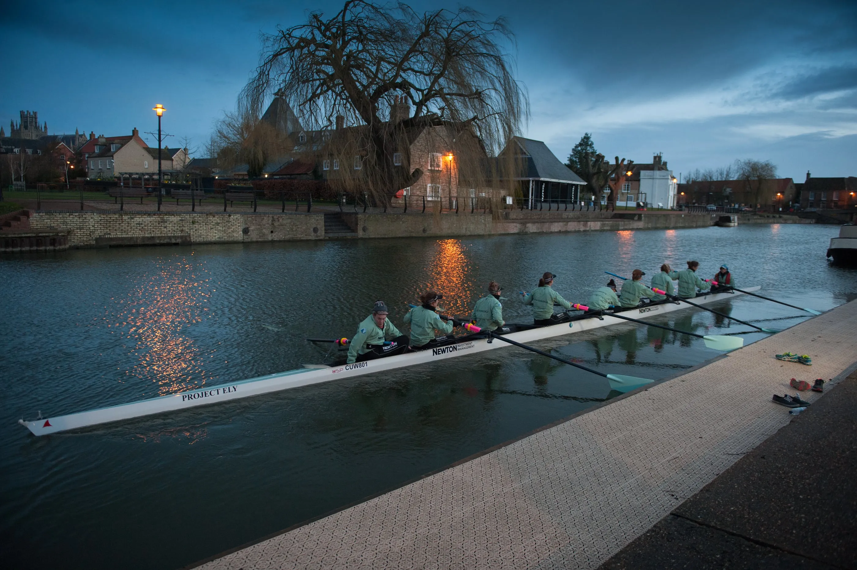 A rowing eight on the water at dawn, photographed against a dark sky