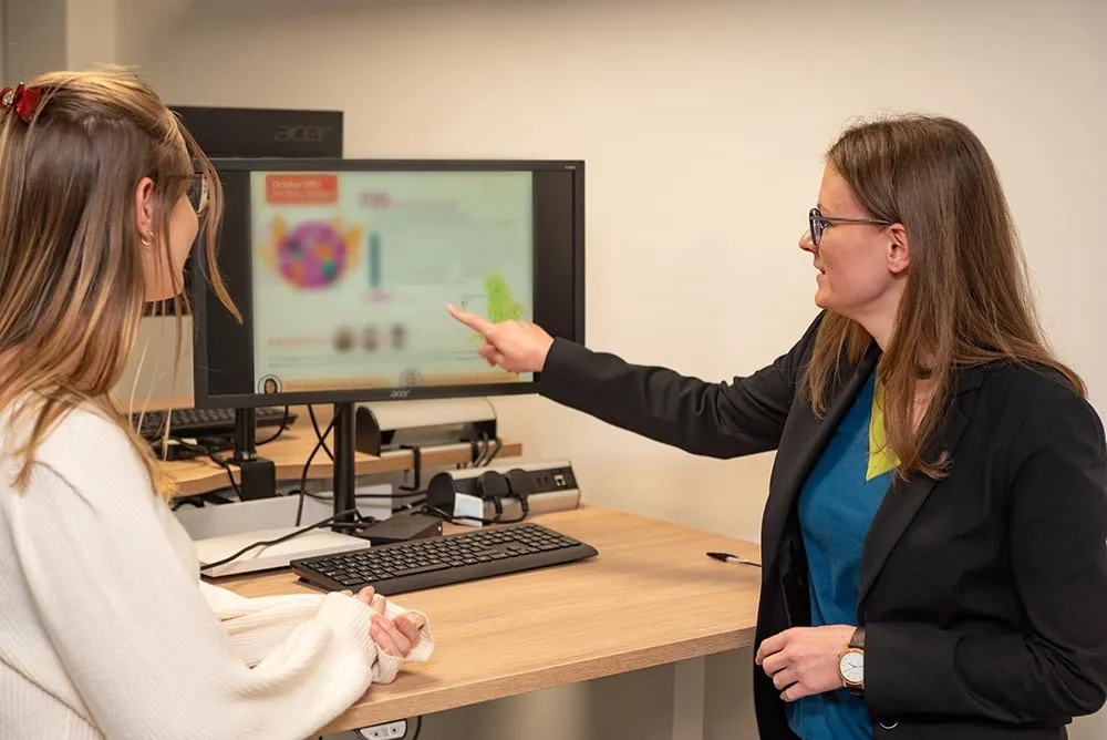 A colleague explaining something on a monitor