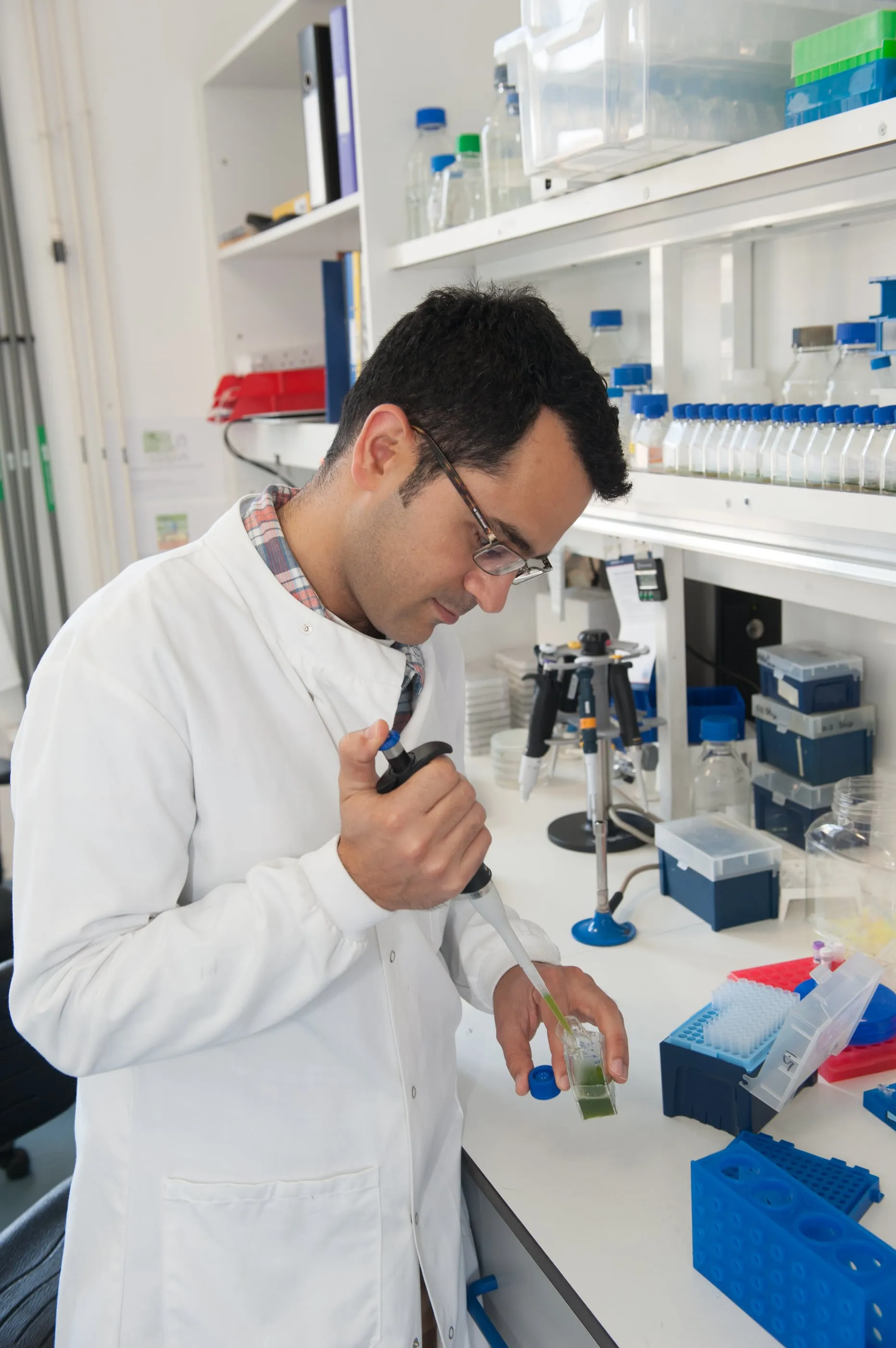 A scientist working at a laboratory bench surrounded by reagent bottles